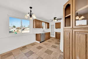 Kitchen featuring sink, white refrigerator, stainless steel dishwasher, pendant lighting, and ceiling fan with notable chandelier