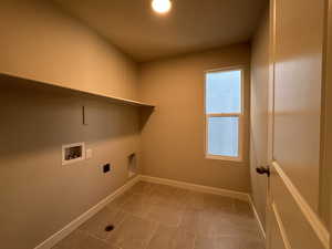 Clothes washing area with tile patterned floors, washer hookup, and electric dryer hookup