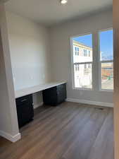 Unfurnished office featuring built in desk and dark hardwood / wood-style flooring