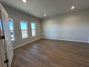 Empty room with dark hardwood / wood-style flooring and a textured ceiling