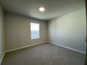 Carpeted spare room featuring a textured ceiling