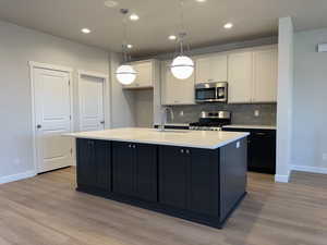 Kitchen with white cabinetry, an island with sink, appliances with stainless steel finishes, and sink