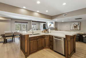 Kitchen featuring dishwasher, sink, a kitchen island with sink, and light hardwood / wood-style flooring