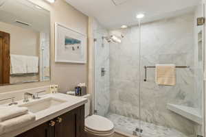 Bathroom with an enclosed shower, vanity, and toilet