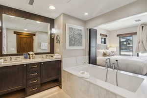 Bathroom featuring vanity, tile patterned flooring, and tiled bath