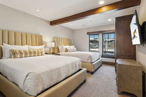 Bedroom with light colored carpet, beam ceiling, and access to outside