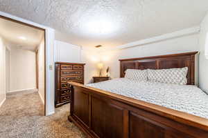 Bedroom with light colored carpet and a textured ceiling