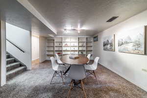 Dining area with built in shelves, track lighting, a textured ceiling, and carpet