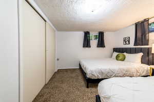 Bedroom with carpet floors, a closet, and a textured ceiling