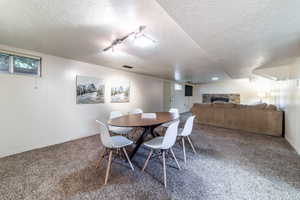 Carpeted dining space with a fireplace and a textured ceiling