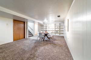 Unfurnished dining area with carpet, a textured ceiling, and built in shelves