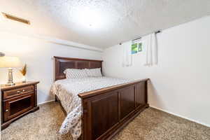 Carpeted bedroom featuring a textured ceiling