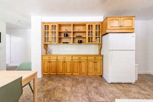 Kitchen with decorative backsplash, white fridge, and a textured ceiling