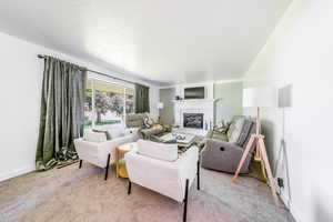 Carpeted living room featuring a fireplace and a textured ceiling