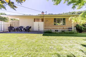 Rear view of property featuring a lawn and a patio