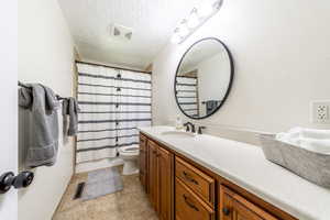 Full bathroom featuring toilet, a textured ceiling, vanity, shower / bathtub combination with curtain, and tile patterned flooring