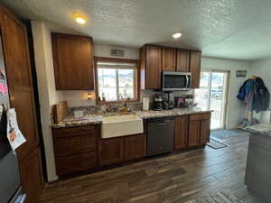 Kitchen with dark wood-type flooring, appliances with stainless steel finishes, sink, and plenty of natural light