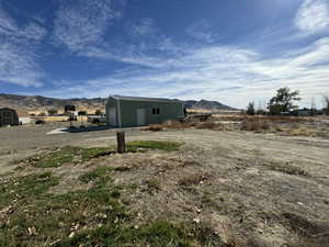 View of yard featuring a garage, an outdoor structure, a mountain view, and a rural view