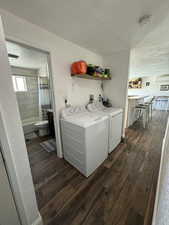 Laundry area with dark wood-type flooring, independent washer and dryer, and a textured ceiling