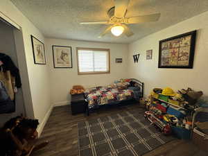 Bedroom with dark wood-type flooring, ceiling fan, and a textured ceiling