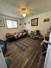 Bedroom with ceiling fan, dark hardwood / wood-style floors, and a textured ceiling