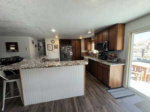 Kitchen with sink, dark wood-type flooring, light stone countertops, and appliances with stainless steel finishes