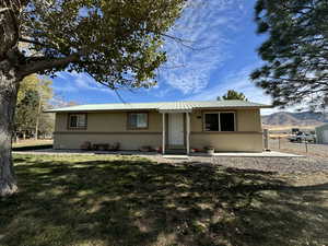 Single story home featuring a mountain view, a patio area, and a front lawn