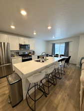 Kitchen featuring sink, a breakfast bar area, a center island with sink, appliances with stainless steel finishes, and white cabinets