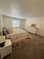 Bedroom featuring dark colored carpet and a textured ceiling