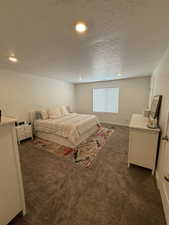 Bedroom with a textured ceiling and dark colored carpet