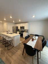 Dining space featuring sink, a textured ceiling, and light wood-type flooring