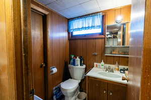 Bathroom featuring vanity, wood walls, and toilet