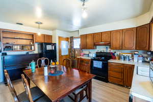 Kitchen with pendant lighting, backsplash, light wood-type flooring, and black appliances