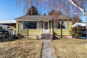 Bungalow featuring a front yard and a carport