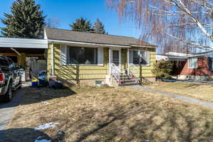 View of front of property featuring a front yard and a carport