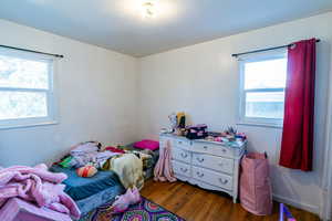 Bedroom featuring dark wood-type flooring and multiple windows