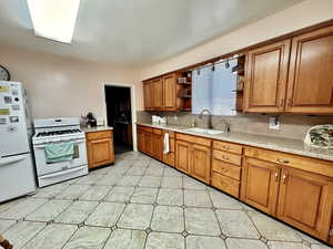 Kitchen featuring sink, white appliances, and decorative backsplash