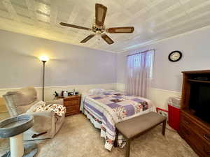 Carpeted bedroom with ornamental molding and ceiling fan