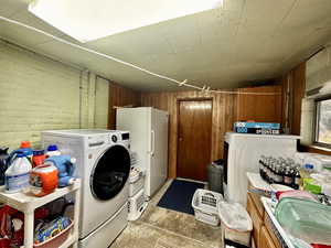 Washroom featuring washer and dryer, brick wall, sink, and wood walls