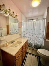 Bathroom featuring vanity, toilet, tile walls, and a textured ceiling