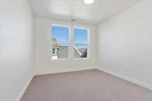 Carpeted spare room featuring a textured ceiling