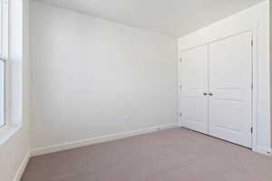 Unfurnished bedroom featuring light colored carpet and a closet