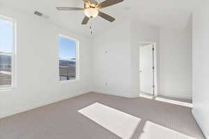 Carpeted empty room featuring vaulted ceiling and ceiling fan