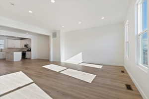 Unfurnished living room featuring sink, light hardwood / wood-style flooring, and a wealth of natural light