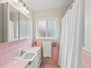 Bathroom with vanity, tile patterned flooring, and tile walls