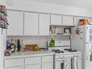 Kitchen with white cabinetry and white appliances