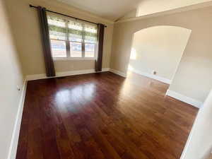 Unfurnished room featuring lofted ceiling and dark hardwood / wood-style flooring