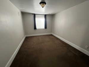 Unfurnished room featuring dark carpet