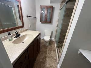 Bathroom featuring vanity, a shower with shower door, and toilet