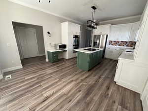 Kitchen with stainless steel appliances, a center island, green cabinets, and white cabinets